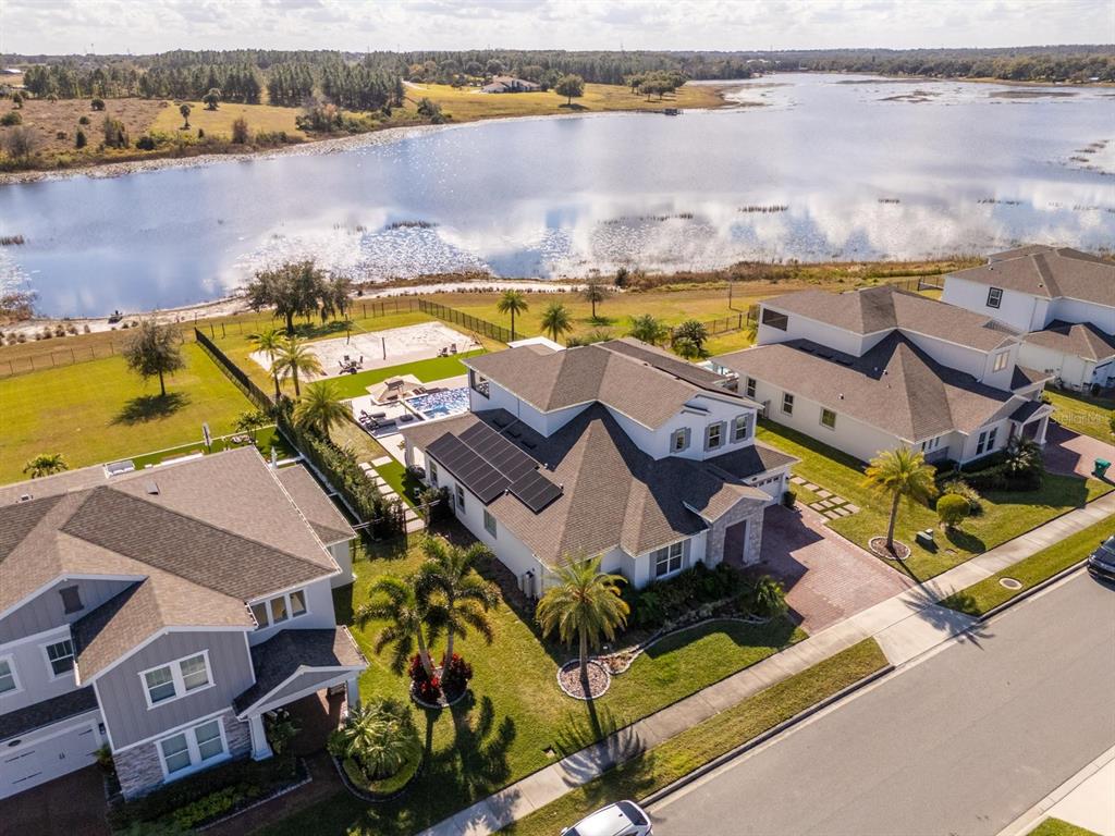 An aerial view of a suburban house with solar panels, a pool, and a lake — 16870 SANCTUARY DRIVE, WINTER GARDEN, FL