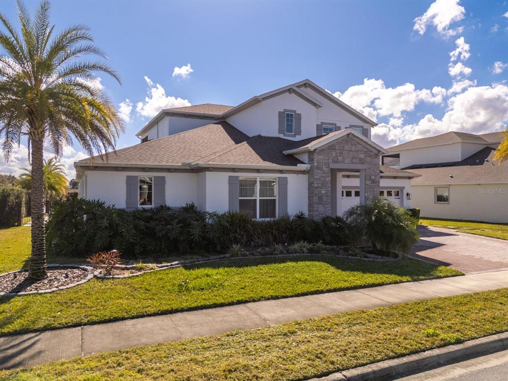 A two-story suburban house features a stone-accented entryway, gray shutters, and a palm tree — 16870 SANCTUARY DRIVE, WINTER GARDEN, FL