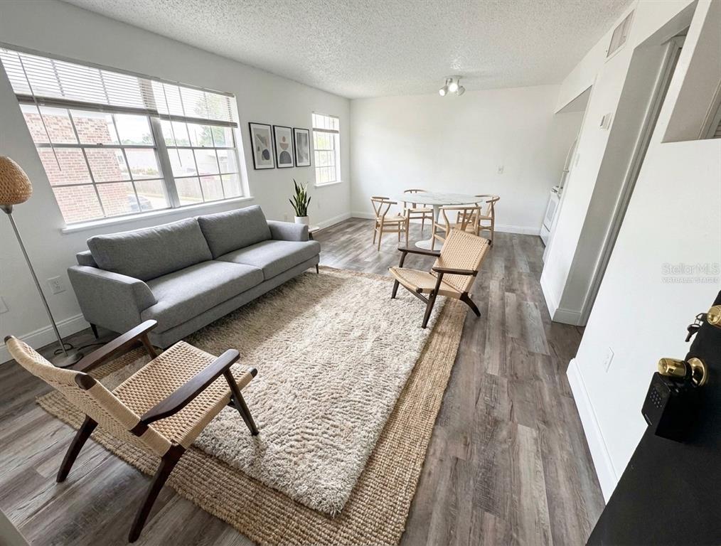 An interior view of a room with wood-look flooring and a black apartment door — 5317 CURRY FORD ROAD UNIT O201, ORLANDO, FL