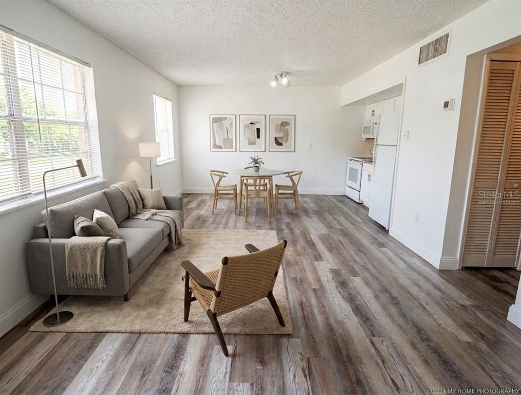 An open-concept living and kitchen area features wood-look flooring and white walls — 5317 CURRY FORD ROAD UNIT O201, ORLANDO, FL