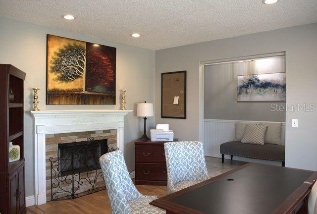A home office features a fireplace, a desk with two patterned chairs, and a small alcove — 3486 HAWKIN DRIVE, KISSIMMEE, FL