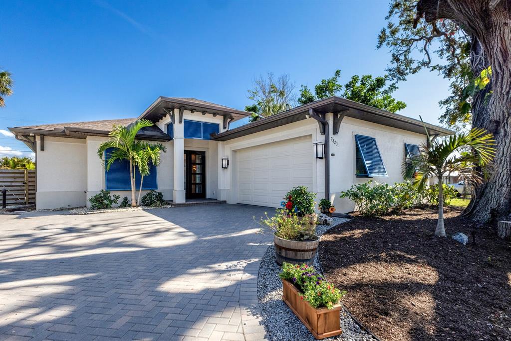 A single-story house with a paved driveway, white stucco walls, blue shutters, and a garage — 2823 MARSHALL DRIVE, SARASOTA, FL