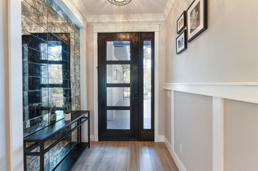 An entryway features a dark wood front door, a mirrored wall, and a console table — 2823 MARSHALL DRIVE, SARASOTA, FL