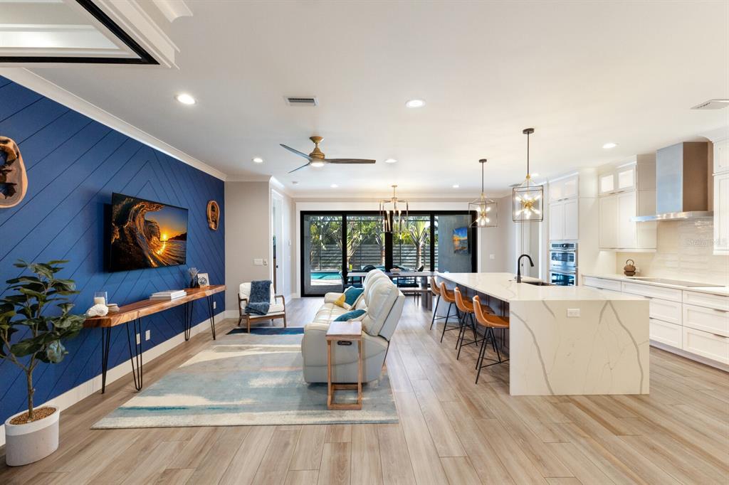 An open-concept living room and kitchen featuring a blue accent wall and marble island — 2823 MARSHALL DRIVE, SARASOTA, FL
