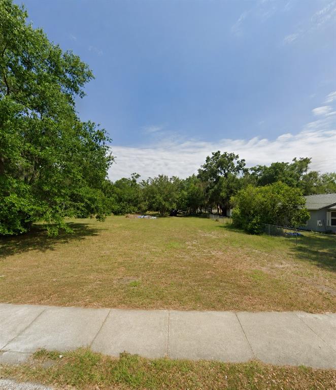 A vacant, grassy residential lot is bordered by trees and a sidewalk — 711 PINE, MOUNT DORA, FL