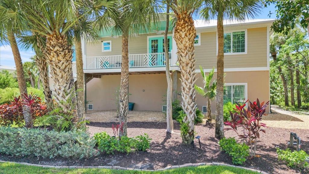 A two-story house with a raised deck, palm trees, and landscaping in the front yard — 9277 BELDING DRIVE, SANIBEL, FL