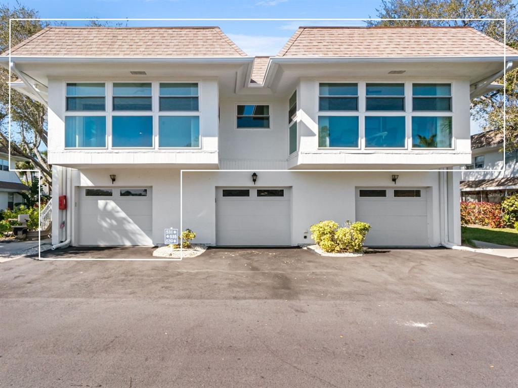 A two-story building features three garage doors on the ground level and large windows above — 531 SUTTON PLACE, LONGBOAT KEY, FL