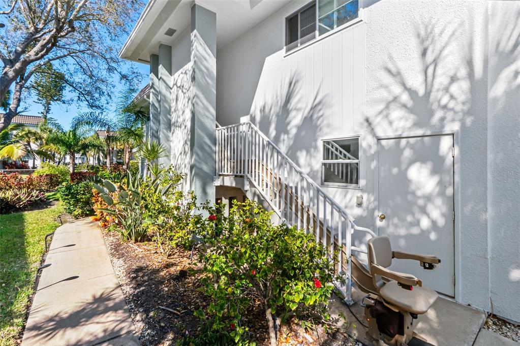 An exterior view shows a white building with a staircase, a chair lift, and landscaping — 531 SUTTON PLACE, LONGBOAT KEY, FL