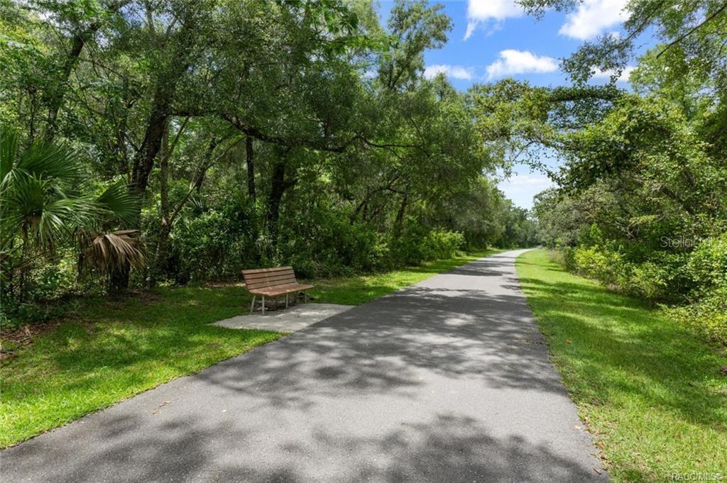 A paved walking path winds through a wooded area with a wooden bench nearby — 4855 N HIGHLAND PARK DRIVE, HERNANDO, FL
