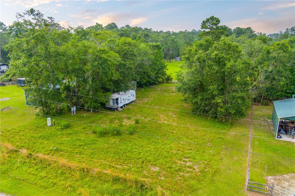 An aerial view shows a grassy lot with a parked RV and surrounding trees — 400 COASTAL OAK LANE NW, STEINHATCHEE, FL