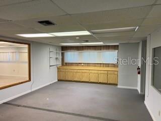 An office space features gray carpeting, light wood cabinetry, and a large window with blinds — 1830 NE 2ND STREET UNIT 1, GAINESVILLE, FL