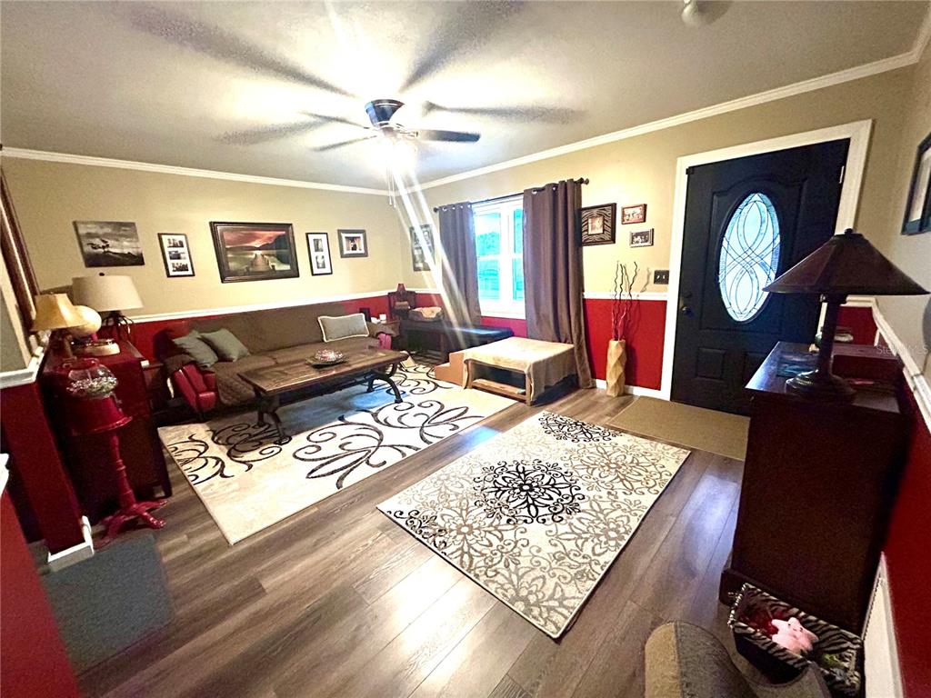 A living room features wood-look flooring, a red and beige wall color scheme, and two rugs — 2210 MURDOCK BOULEVARD, ORLANDO, FL