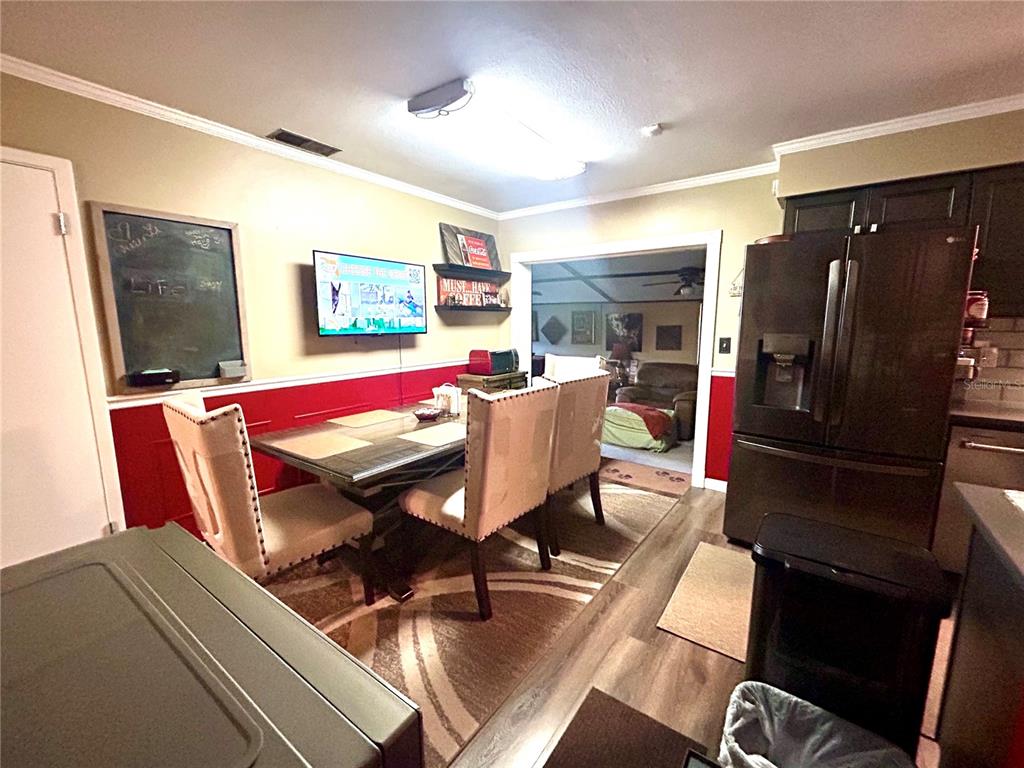 A dining area features a table with four chairs, a wall-mounted television, and red wainscoting — 2210 MURDOCK BOULEVARD, ORLANDO, FL