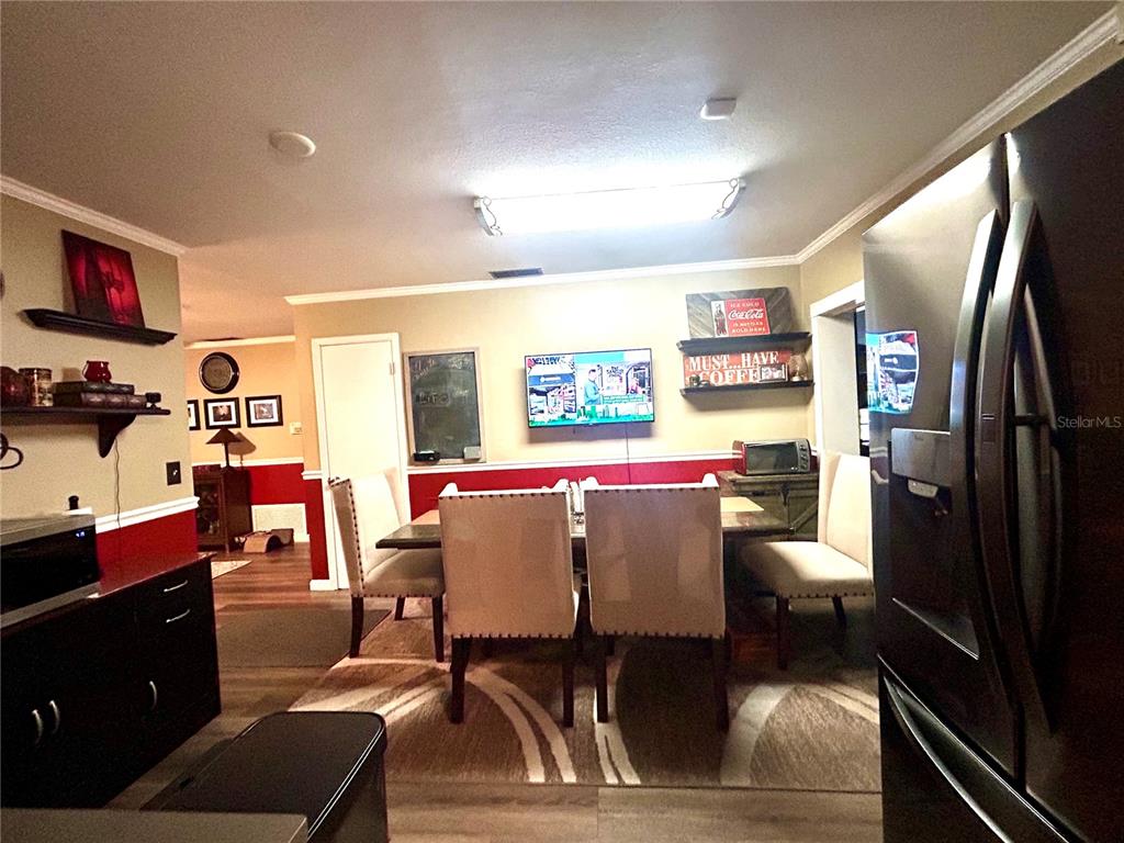 A dining area features a table with four upholstered chairs, a wall-mounted television, and red wainscoting — 2210 MURDOCK BOULEVARD, ORLANDO, FL