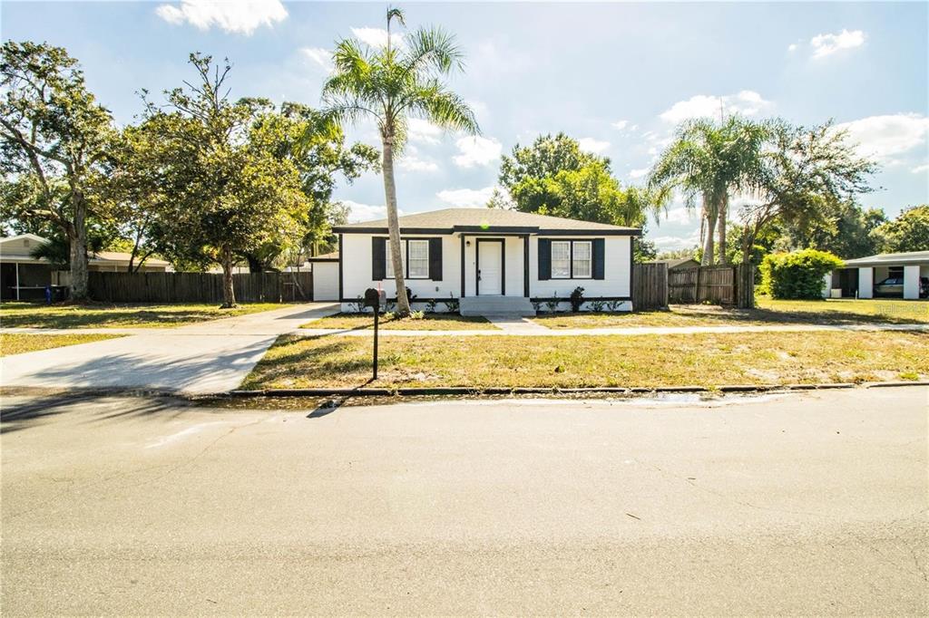 A single-story white house with black trim and a palm tree in the front yard — 1851 E ELM ROAD, LAKELAND, FL