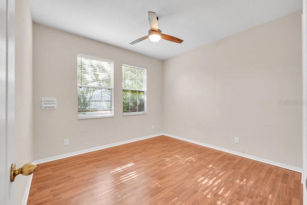 An empty bedroom with light-colored walls, wood-look flooring, two windows, and a ceiling fan — 6105 GANNETSIDE PLACE, LITHIA, FL
