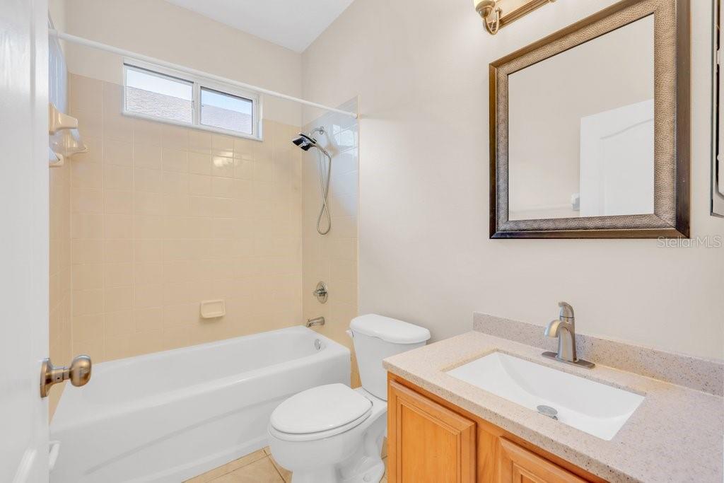 A bathroom featuring a white bathtub with a shower, a toilet, and a wood vanity — 6105 GANNETSIDE PLACE, LITHIA, FL