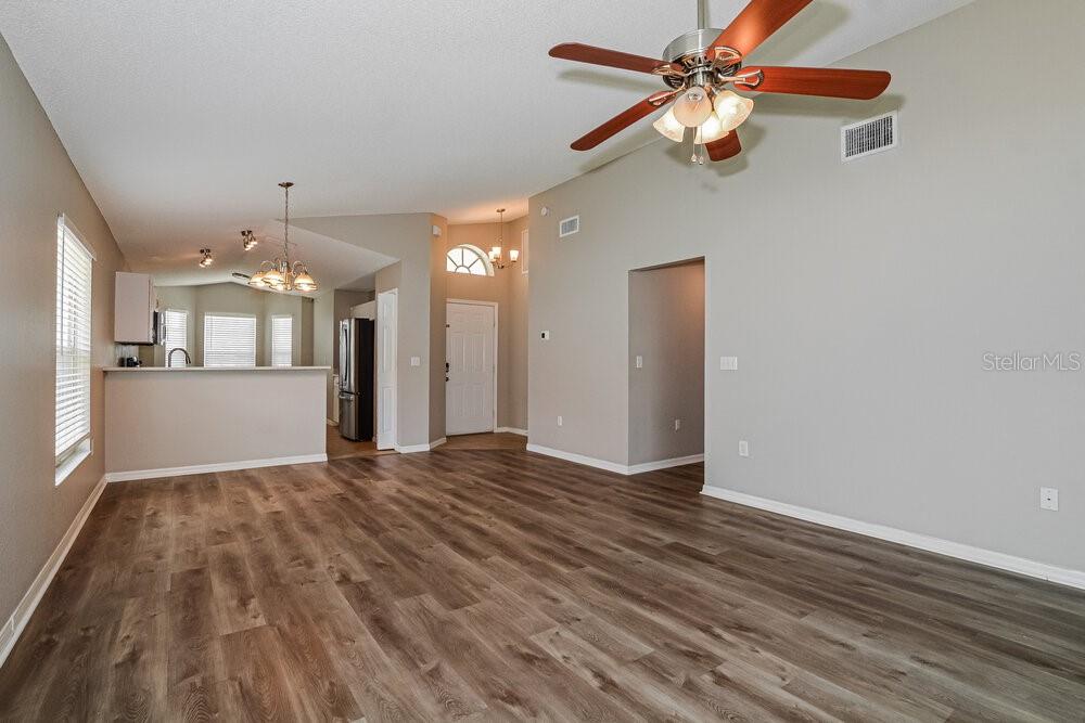 An open-concept living area features wood-look flooring, a ceiling fan, and a kitchen pass-through window — 3740 IMPERIAL DRIVE, WINTER HAVEN, FL