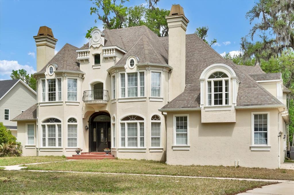 A two-story stucco house with a shingled roof, multiple chimneys, and arched window accents — 48 AUDUBON LANE, FLAGLER BEACH, FL