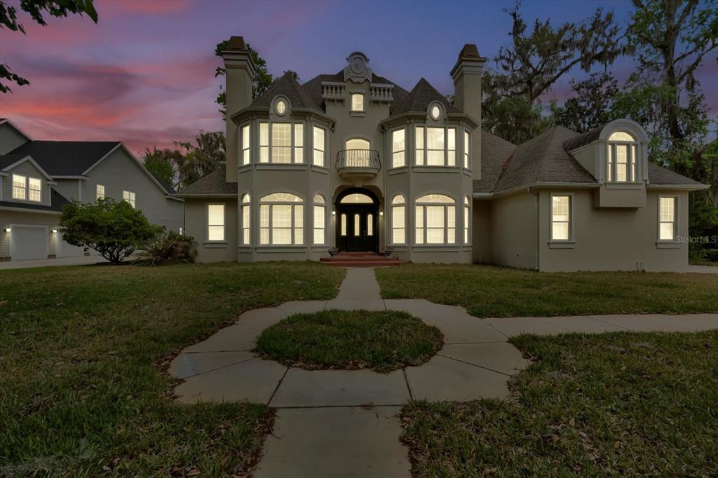A two-story house with a symmetrical facade, arched entryway, and a paved walkway at dusk — 48 AUDUBON LANE, FLAGLER BEACH, FL