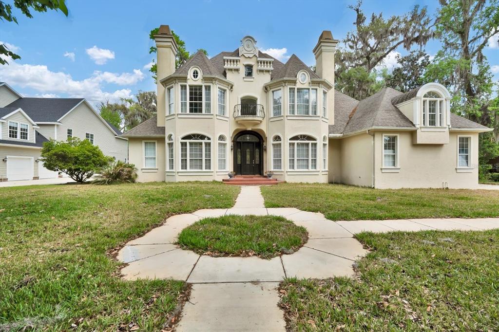 A large, two-story beige house with a symmetrical facade, arched windows, and a circular walkway — 48 AUDUBON LANE, FLAGLER BEACH, FL