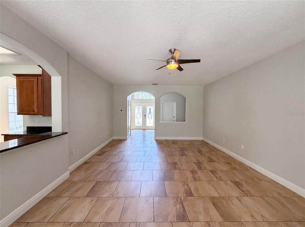 An empty room with gray carpet, light walls, a ceiling fan, and three windows — 12706 GROVEHURST AVENUE, WINTER GARDEN, FL