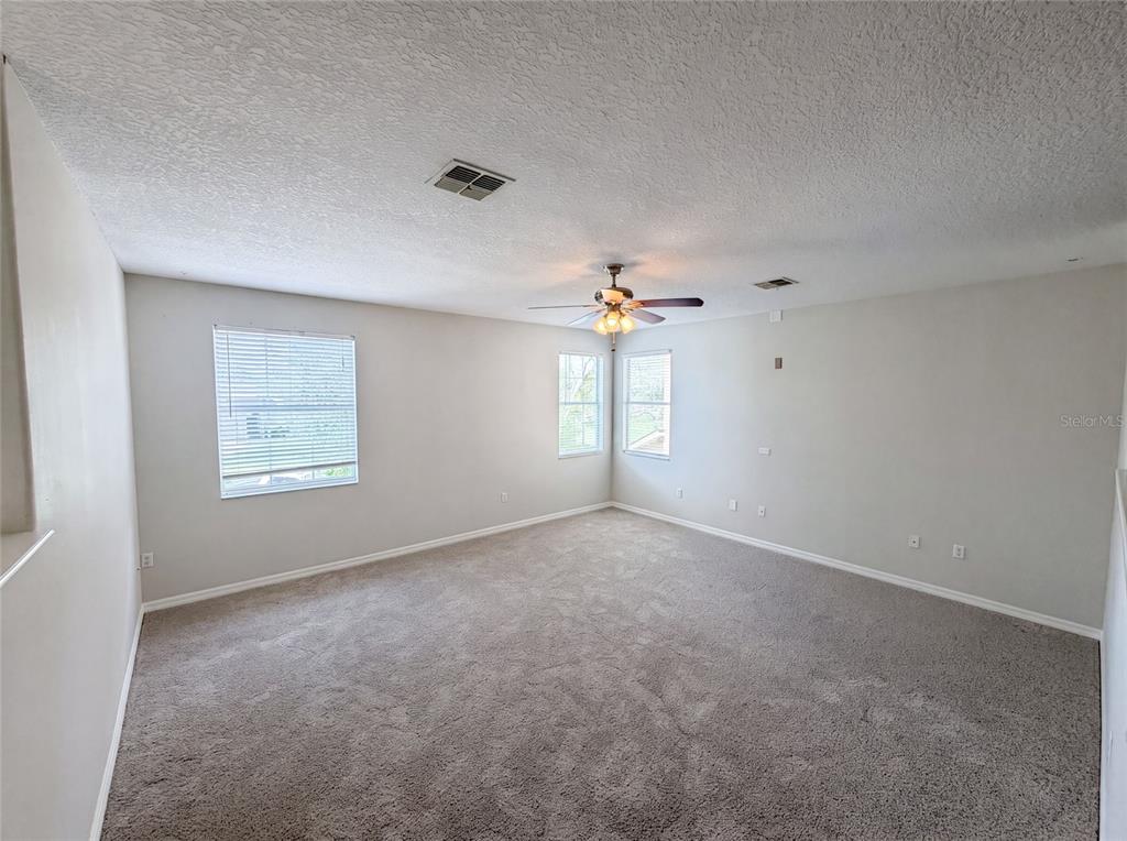 A kitchen features wood cabinets, stainless steel appliances, black countertops, and light-colored tile flooring — 12706 GROVEHURST AVENUE, WINTER GARDEN, FL