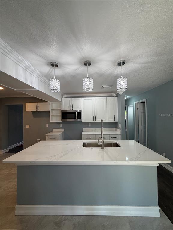 A kitchen features white cabinets, stainless steel appliances, a quartz island, and light blue walls — 682 DURANGO WAY, ALTAMONTE SPRINGS, FL
