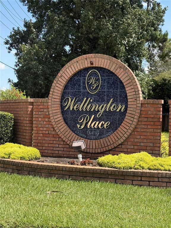 A brick entrance sign for Wellington Place stands in front of trees and green landscaping — 11348 NW 31ST LANE, GAINESVILLE, FL