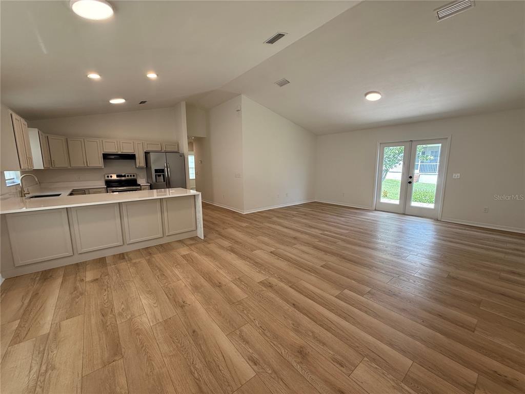 An open-concept kitchen and living area feature light wood-look flooring and white cabinetry — 11348 NW 31ST LANE, GAINESVILLE, FL