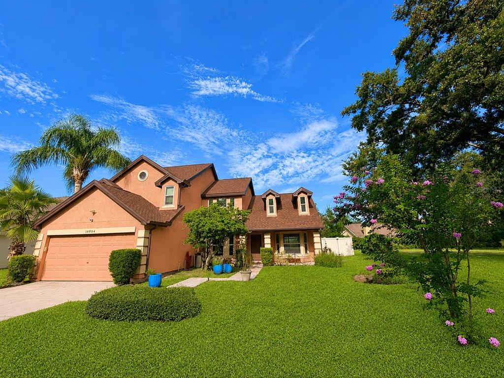 A two-story house with a tan stucco exterior, a brown roof, and a front lawn — 14904 PERRIWINKLE PLACE, TAMPA, FL