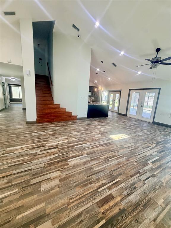 An open-concept living area features wood-look flooring, a wooden staircase, and a kitchen island — 14904 PERRIWINKLE PLACE, TAMPA, FL