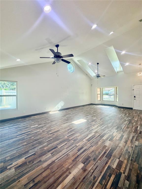 An empty living room features vaulted ceilings, two ceiling fans, and wood-look plank flooring — 14904 PERRIWINKLE PLACE, TAMPA, FL