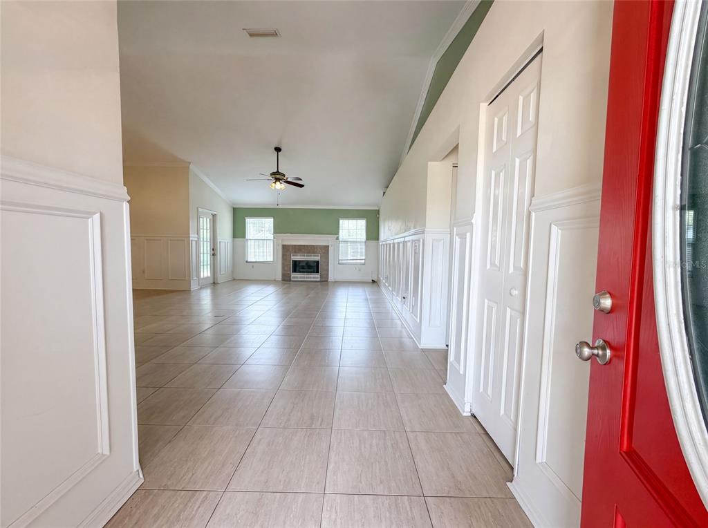 An entryway leads into a spacious living room with tile floors, wainscoting, and a fireplace — 944 NW 87TH DRIVE, GAINESVILLE, FL