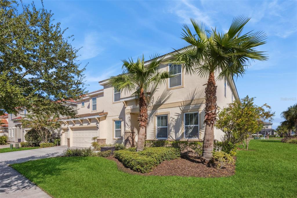 A two-story beige house with a two-car garage and two palm trees in the front — 6000 OAK GREEN LOOP, DAVENPORT, FL