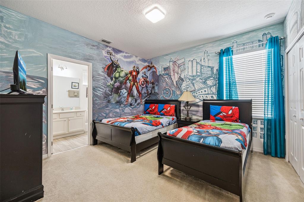 A bedroom features two twin beds, superhero-themed bedding, and a large mural on the walls — 6000 OAK GREEN LOOP, DAVENPORT, FL