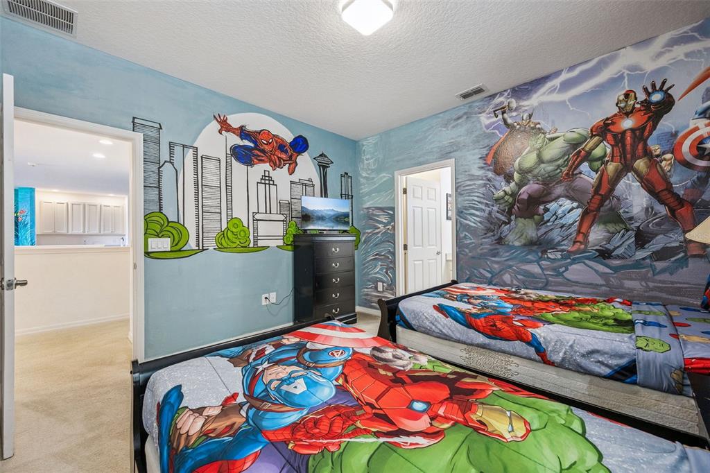 A bedroom features twin beds with superhero bedding and walls decorated with Marvel character murals — 6000 OAK GREEN LOOP, DAVENPORT, FL