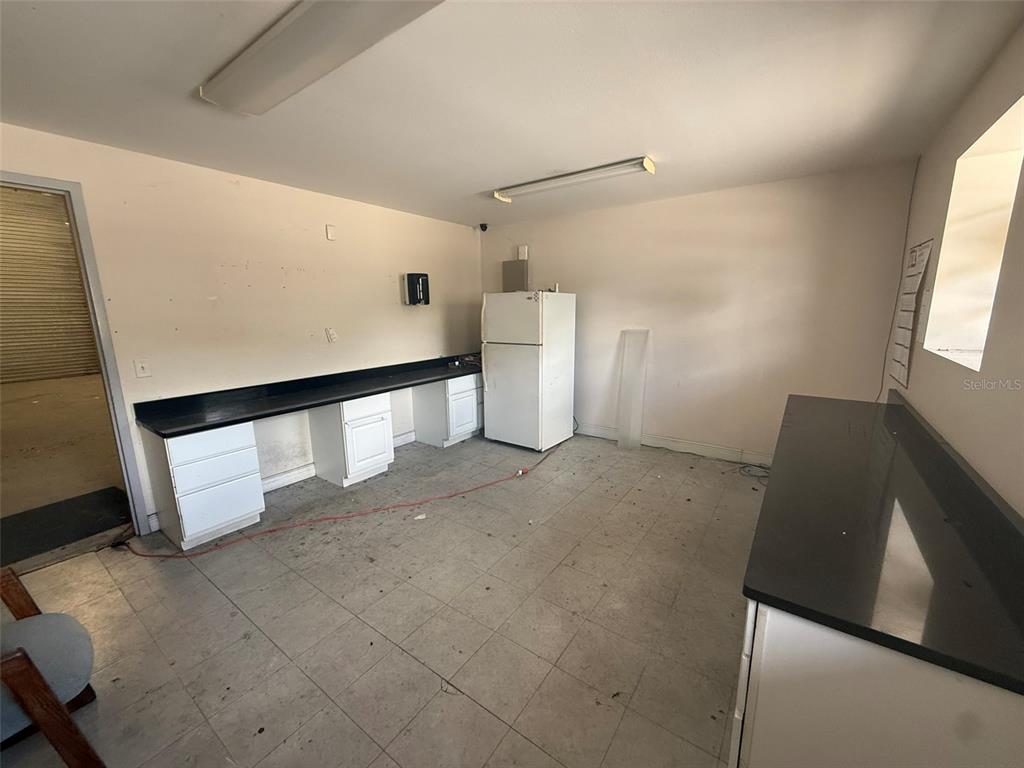 A utility room features white cabinets, black countertops, a white refrigerator, and tiled flooring — 4344 SE 95TH STREET UNIT 1 & 2, OCALA, FL