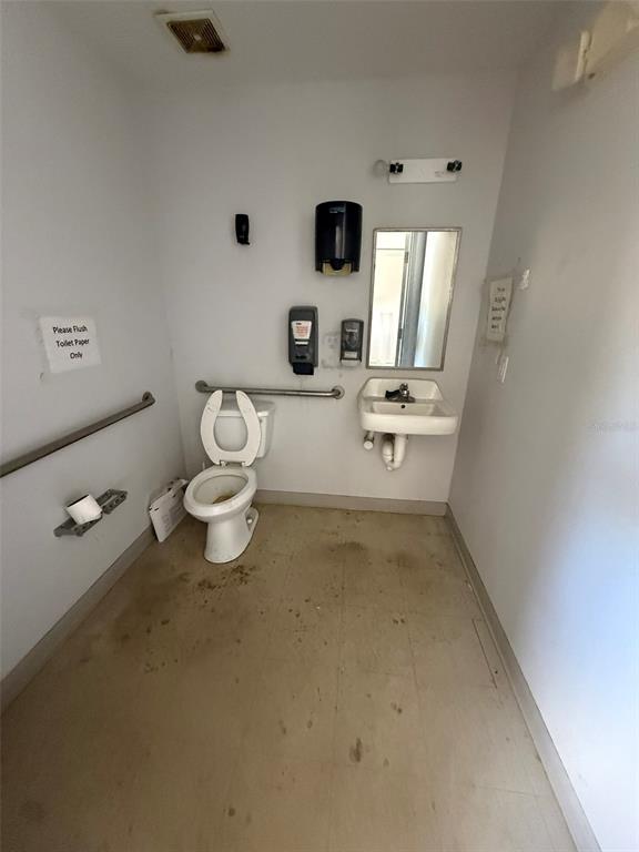 A small, sparse restroom features a white toilet, a wall-mounted sink, and grab bars — 4344 SE 95TH STREET UNIT 1 & 2, OCALA, FL