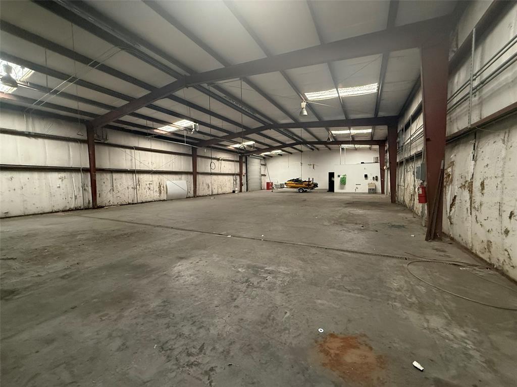 A large, empty industrial warehouse space features concrete floors, exposed steel beams, and skylights — 4344 SE 95TH STREET UNIT 1 & 2, OCALA, FL