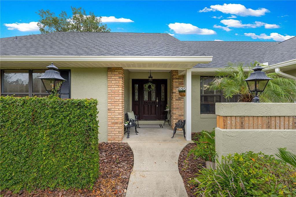 A front entryway features a covered porch, brick columns, and a dark wood front door — 1020 SW 32ND LANE, OCALA, FL