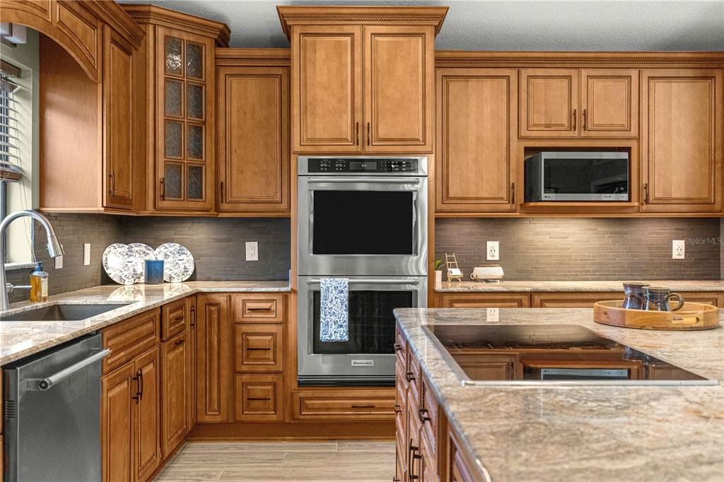 A kitchen features wood cabinets, granite countertops, stainless steel appliances, and a central island — 1020 SW 32ND LANE, OCALA, FL