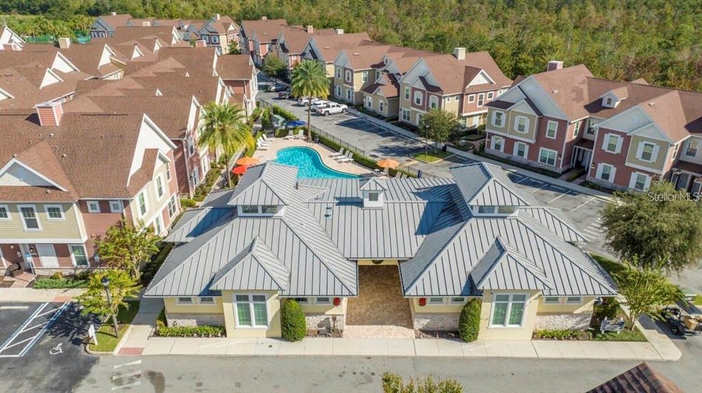 An aerial view shows a community clubhouse with a metal roof and a swimming pool — 7514 SUNVILLE AVENUE, KISSIMMEE, FL