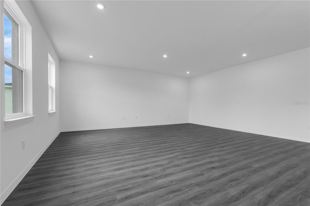 A living room features gray wood-look flooring, a light gray sofa, and a television console — 1342 DUNBLANE WAY NE, PALM BAY, FL