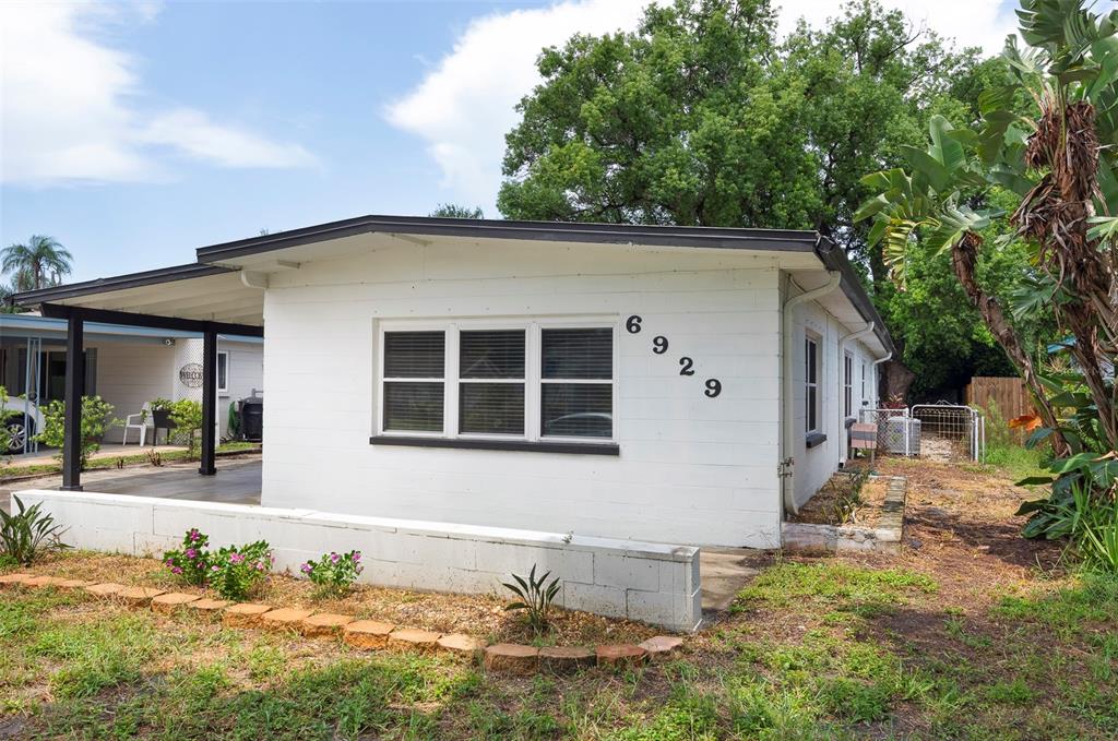 A white, single-story house with a flat roof, a covered porch, and a low block wall — 6929 39TH AVENUE N, ST PETERSBURG, FL