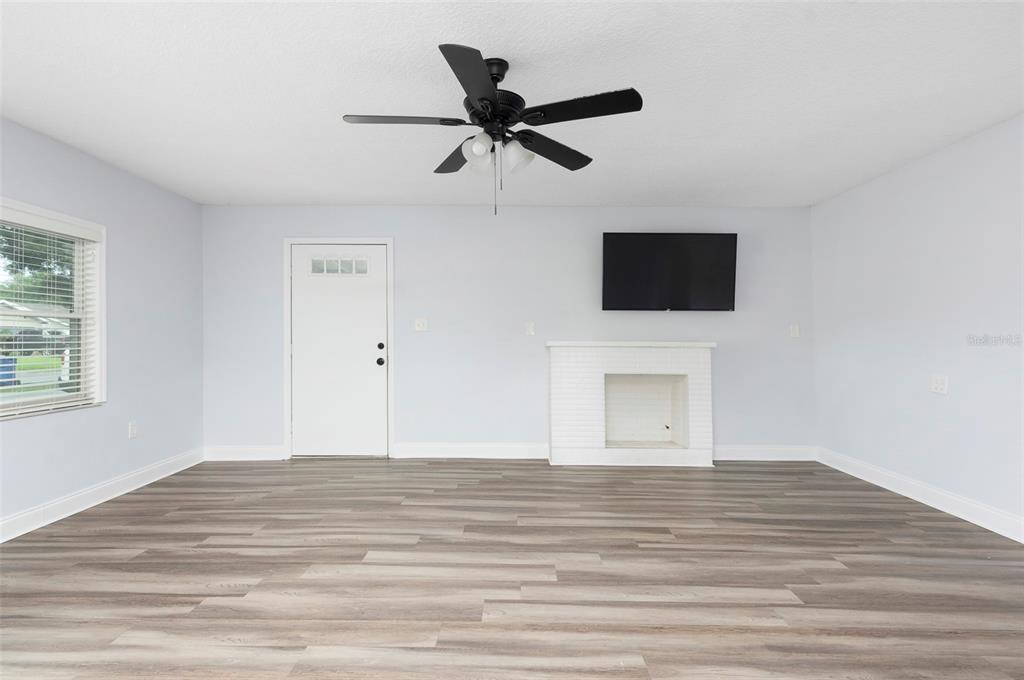 A living room features light gray walls, wood-look flooring, a ceiling fan, and a white fireplace — 6929 39TH AVENUE N, ST PETERSBURG, FL