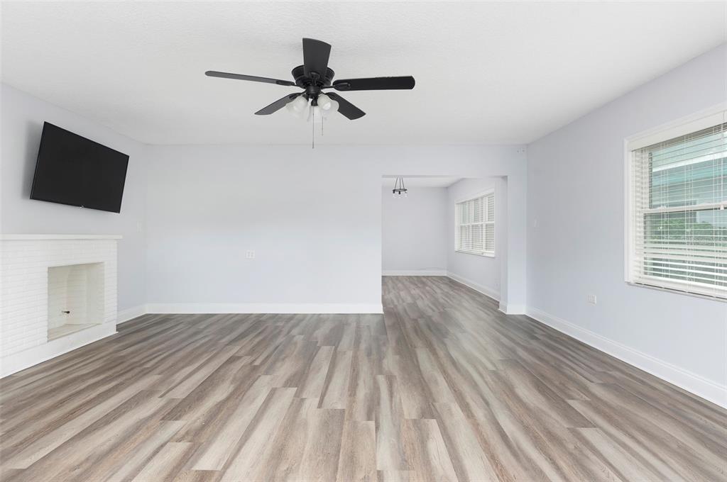 A living room features light gray walls, wood-look flooring, a ceiling fan, and a fireplace — 6929 39TH AVENUE N, ST PETERSBURG, FL