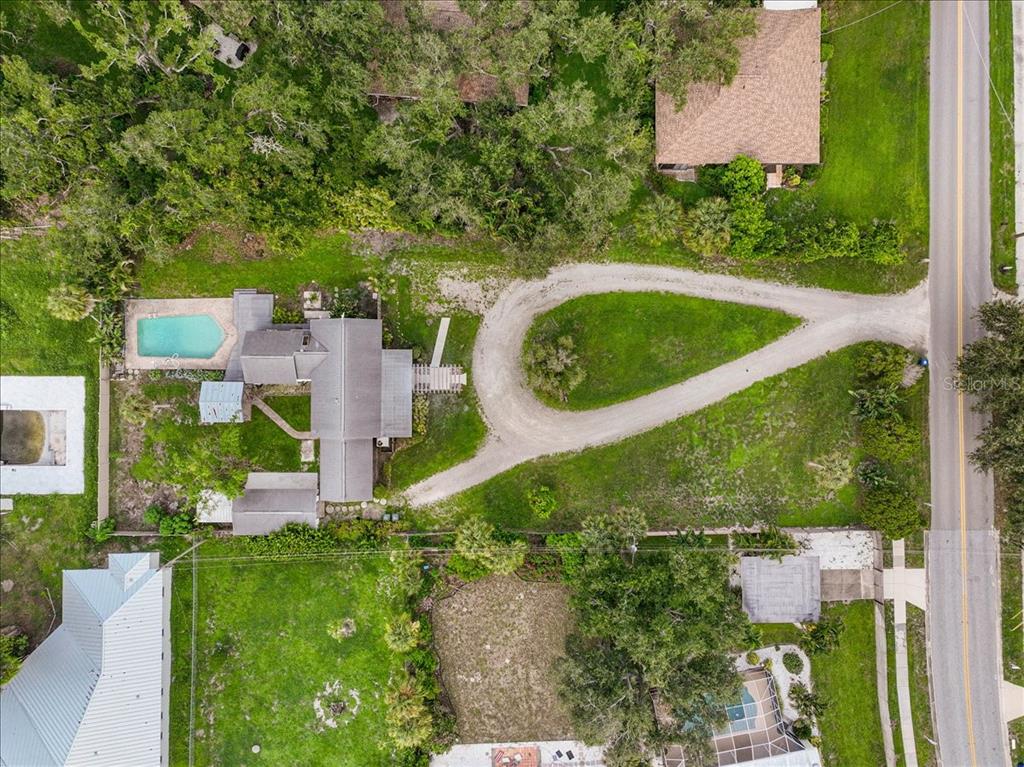 An aerial view shows a suburban neighborhood with houses, green spaces, and a distant coastline — 2404 BISPHAM ROAD, SARASOTA, FL