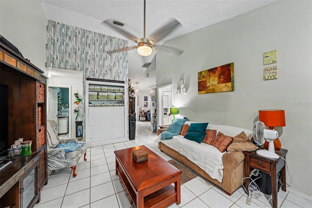 A living room features a vaulted ceiling, tile floors, a ceiling fan, and a sofa — 2250 SPRINGWOOD CIR W, CLEARWATER, FL