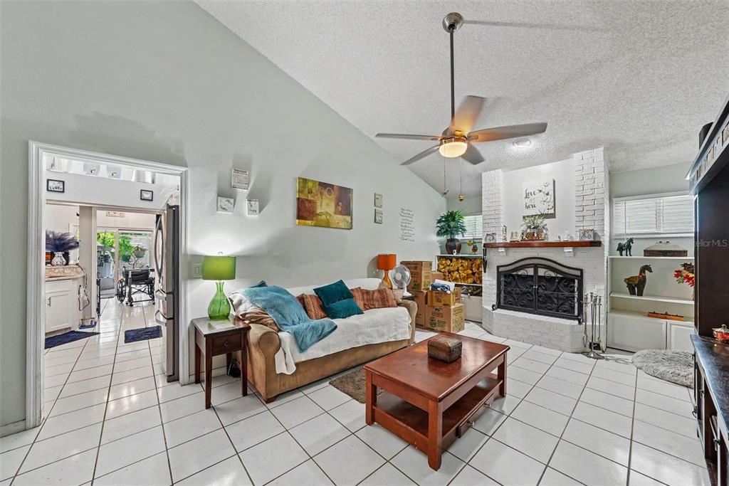 A living room features white tile floors, a vaulted ceiling, and a white brick fireplace — 2250 SPRINGWOOD CIR W, CLEARWATER, FL